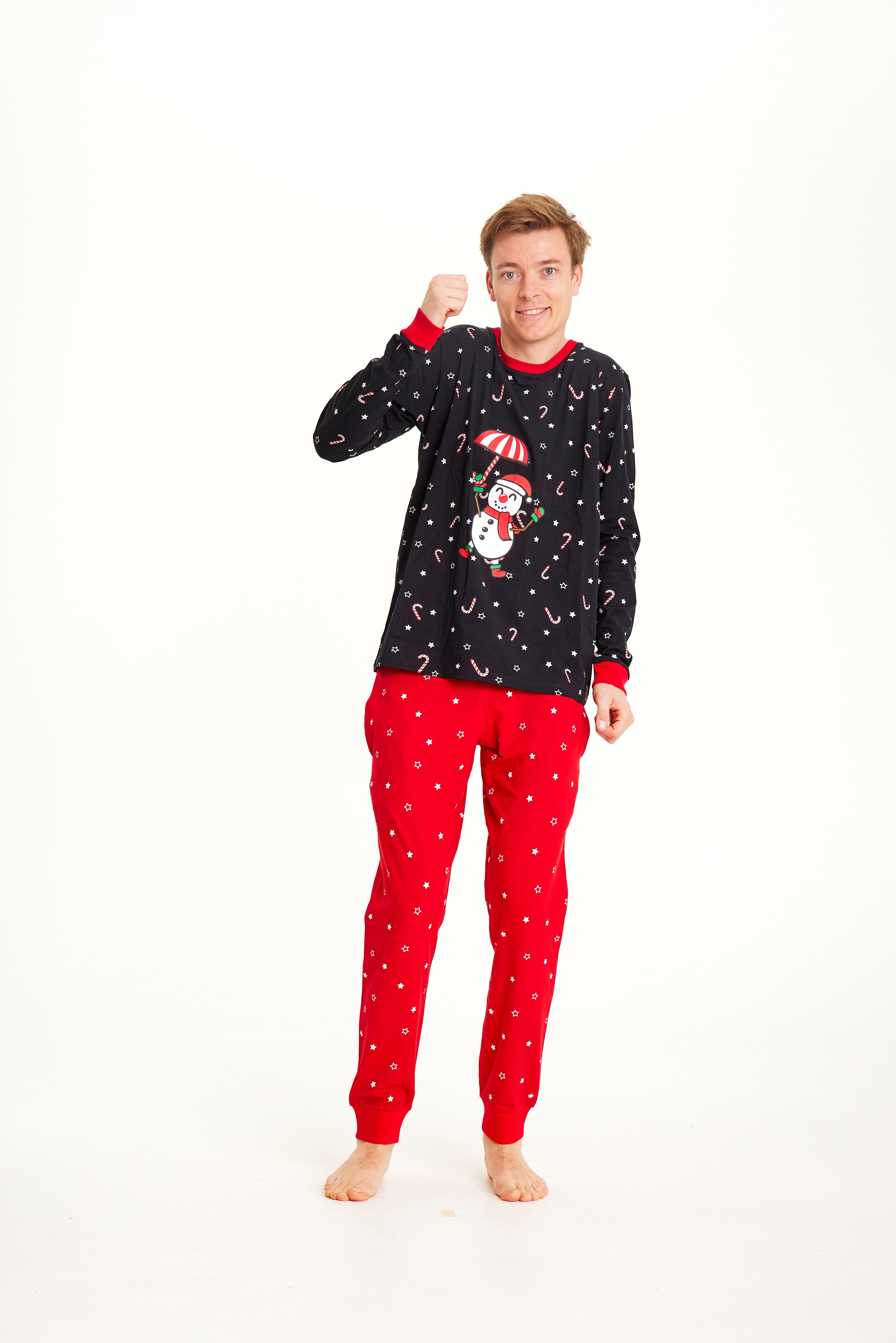 En mann i svart og rød julepyjamas med snømann på.
